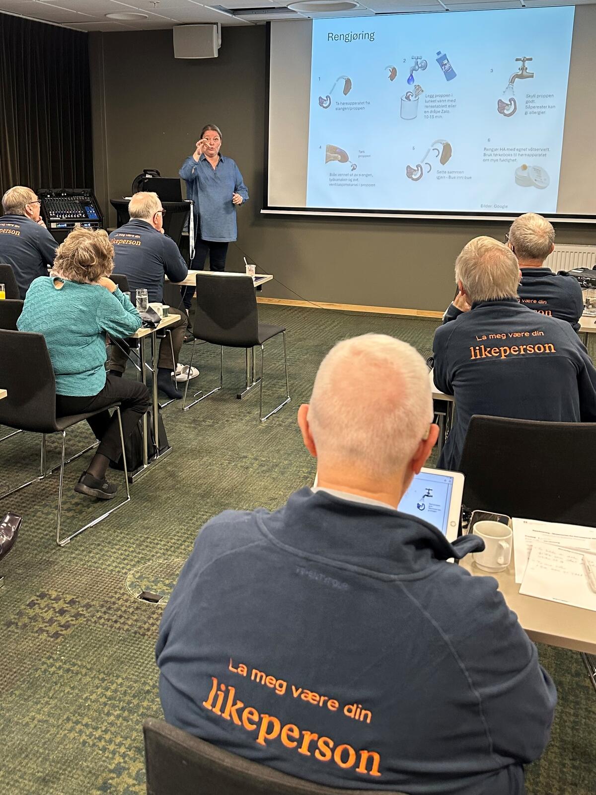Dame holder foredrag for kursdeltakeren med like blå jakker