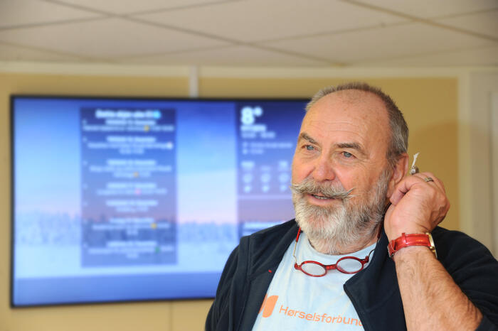 Mann holder høreapparat mot øret