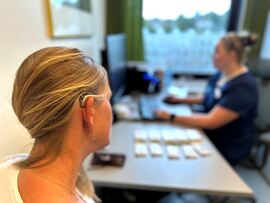 pasient med høreapparat sitter hos audiograf