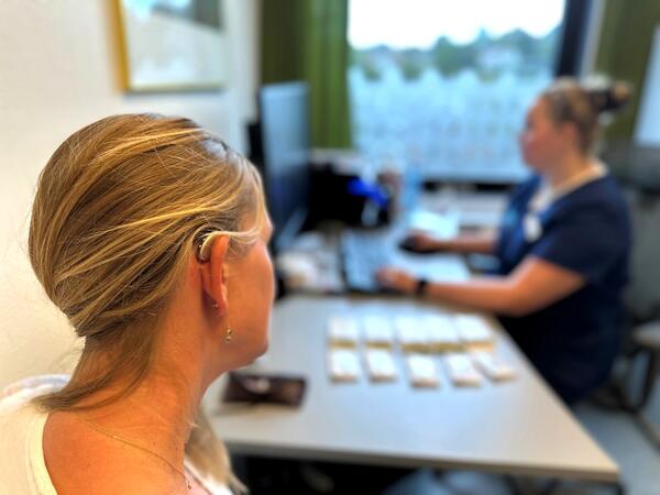 pasient med høreapparat sitter hos audiograf