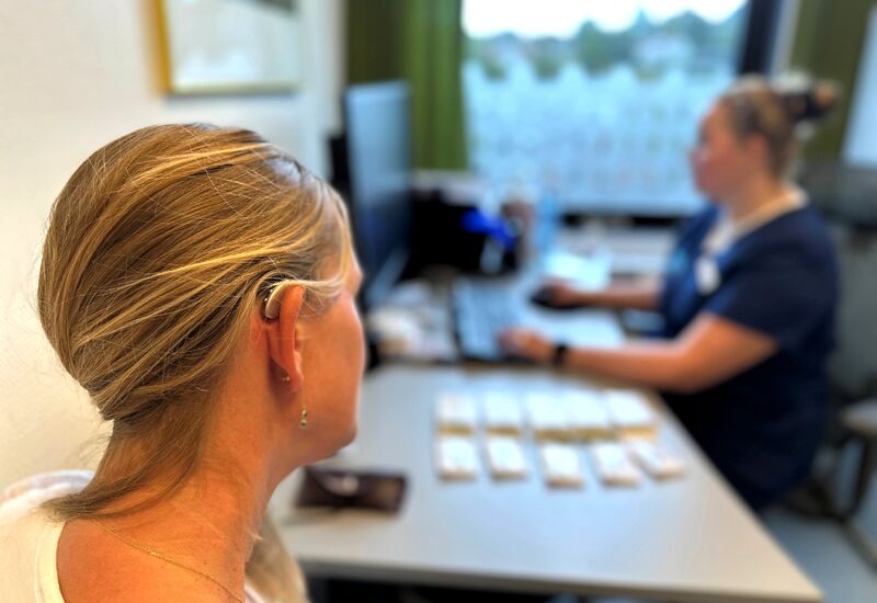 pasient med høreapparat sitter hos audiograf