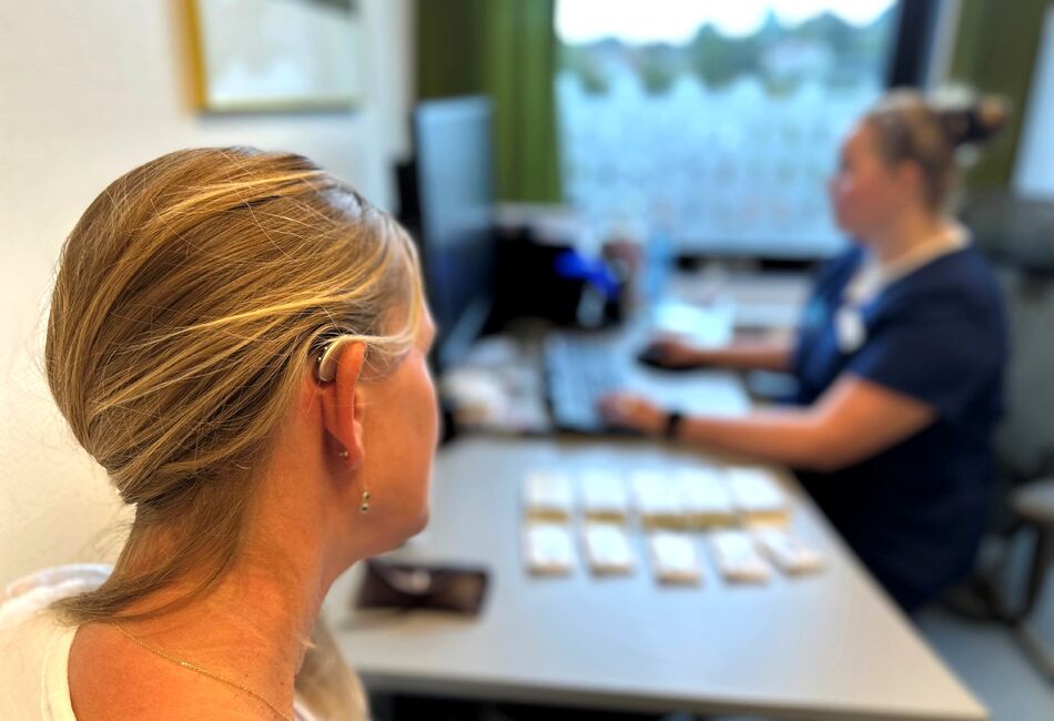 pasient med høreapparat sitter hos audiograf