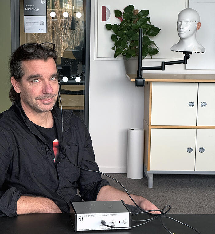 Mann i mørk skjorte med apparat og ledninger