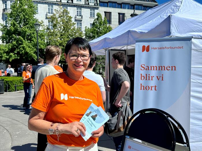 Dame i oransje t-skjorte foran telt