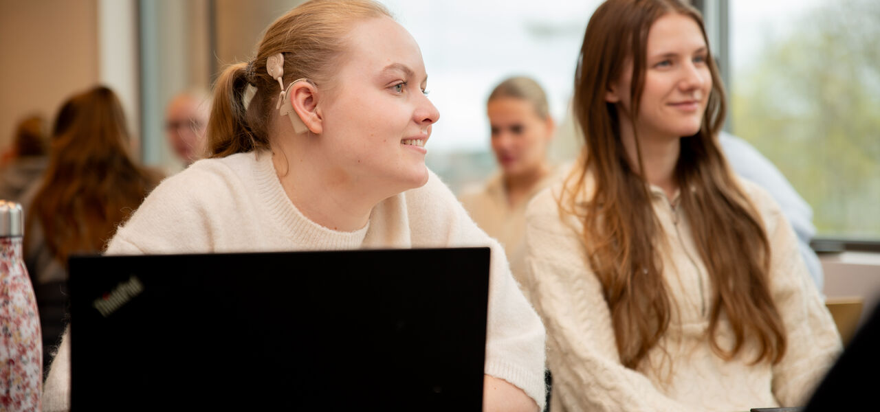 To studenter sitter konsentrert og lytter