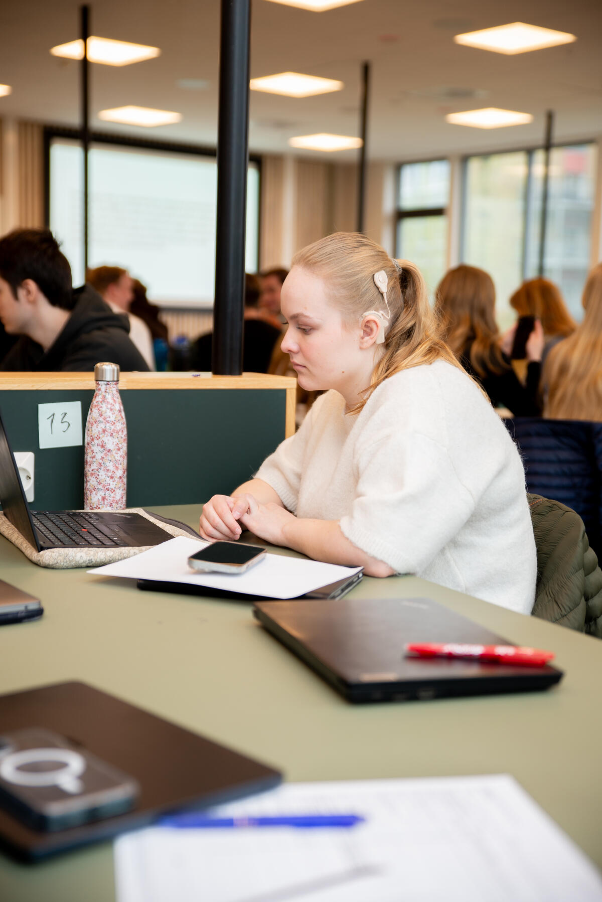 RETT PÅ ØRET. Ved hjelp av mikrofonlyd i CI-apparatet og skrivetolker får Eline med seg det forelesere og medstudenter sier. Student ser på ÅC-skjerm med synlige CI-apparater på siden