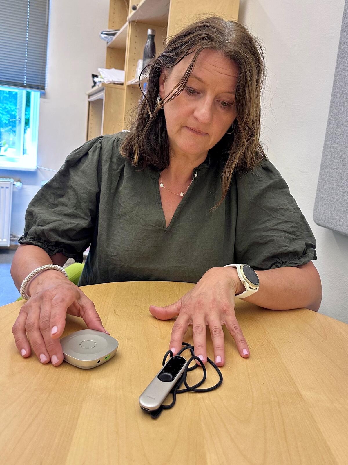 Dame ved et bord viser frem Rogerpen
